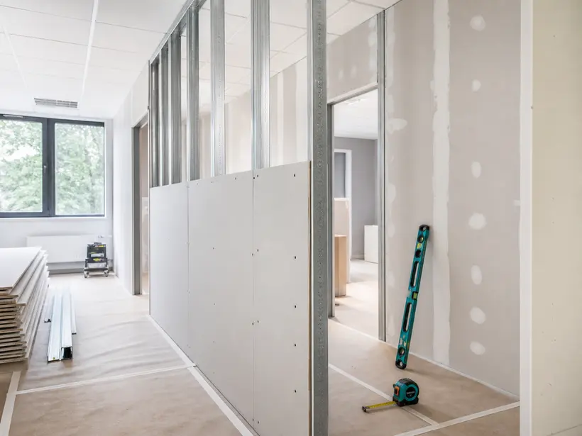 Parede de drywall em instalação com perfis de aço galvanizado e chapas fixadas.